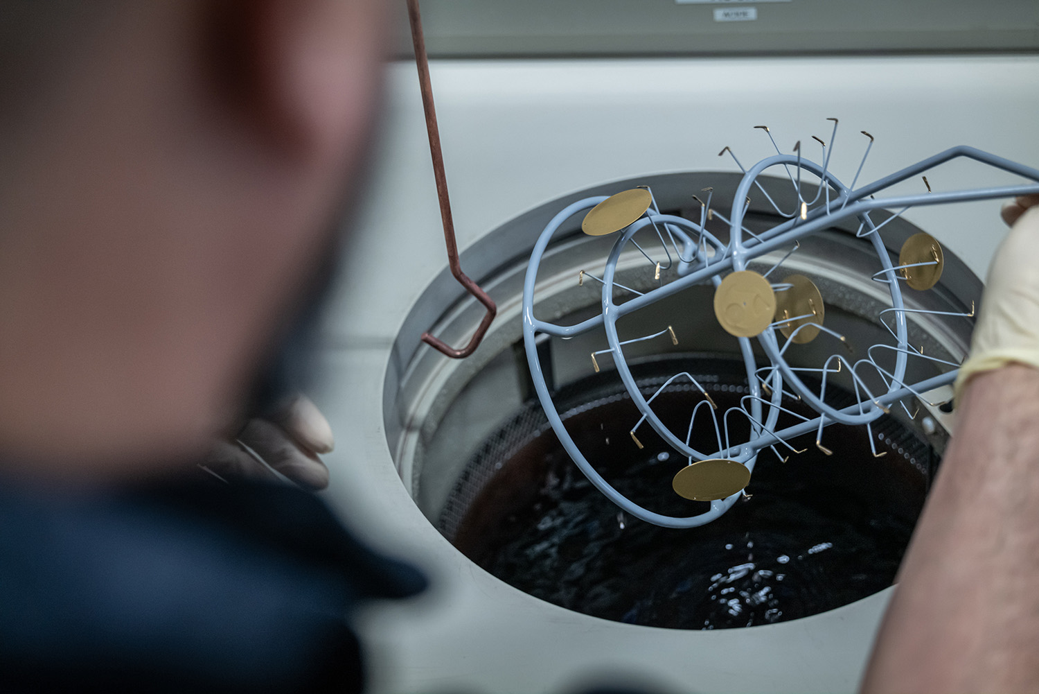 Metal discs on wire rack over galvanising liquid